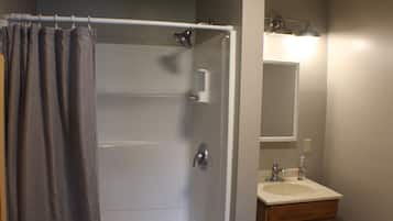 A bathroom with a shower, a sink, and a mirror.