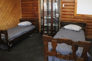 A room with two wooden beds, each with a pillow and a mattress.