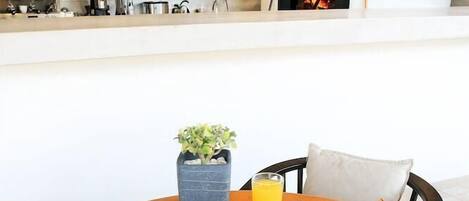 A breakfast table with a variety of food items, a coffee machine, and a pizza oven in the background.
