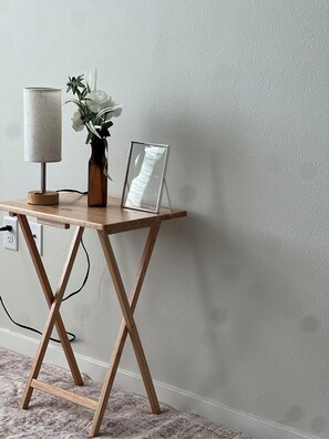 A wooden desk with a lamp, a vase with flowers, and a picture frame against a plain wall. - Cozy 1-bedroom apartment with AC in adorable Davenport (Davenport)