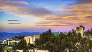 A hotel complex with multiple buildings, surrounded by dense forest and mountains in the background.