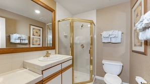 A bathroom with a glass-enclosed shower, a white sink, and a toilet.