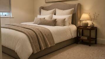 A bedroom with a large bed, a bedside table with a lamp, and a hanging light fixture.