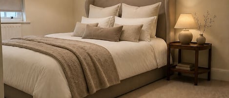 A bedroom with a large bed, a bedside table with a lamp, and a hanging light fixture.