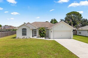 A single-story house with a garage, a small porch, and a well-maintained lawn.
