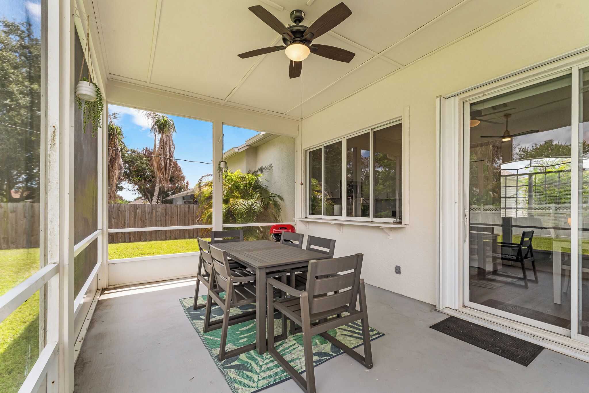 A covered patio with a table and chairs, a ceiling fan, and a view of the backyard.