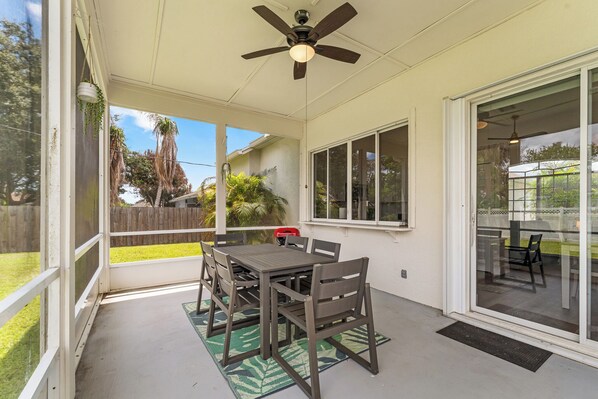 A covered patio with a table and chairs, a ceiling fan, and a view of the backyard.