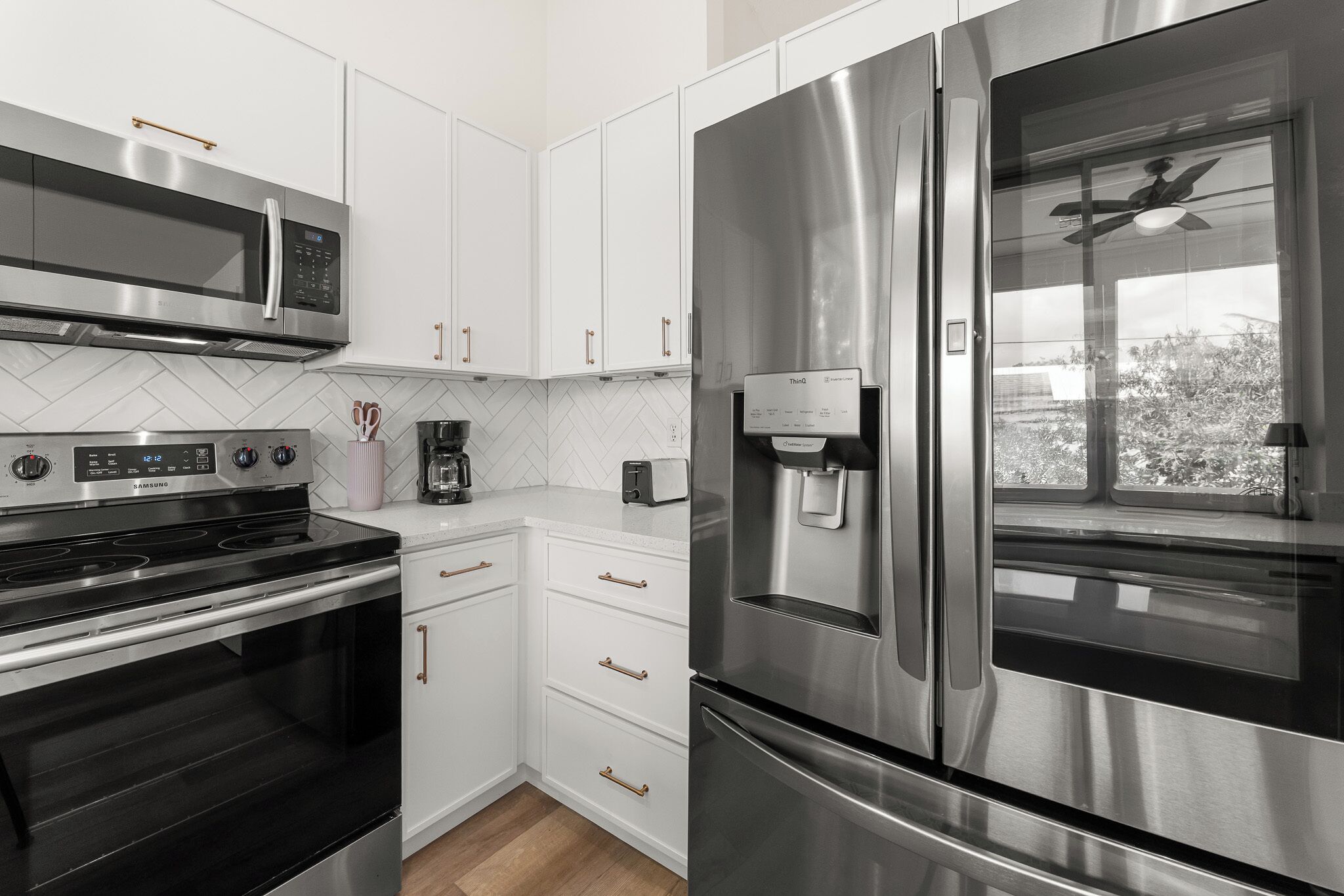 A modern kitchen with stainless steel appliances, white cabinetry, and a built-in water dispenser.