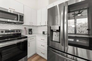 A modern kitchen with stainless steel appliances, white cabinetry, and a built-in water dispenser.