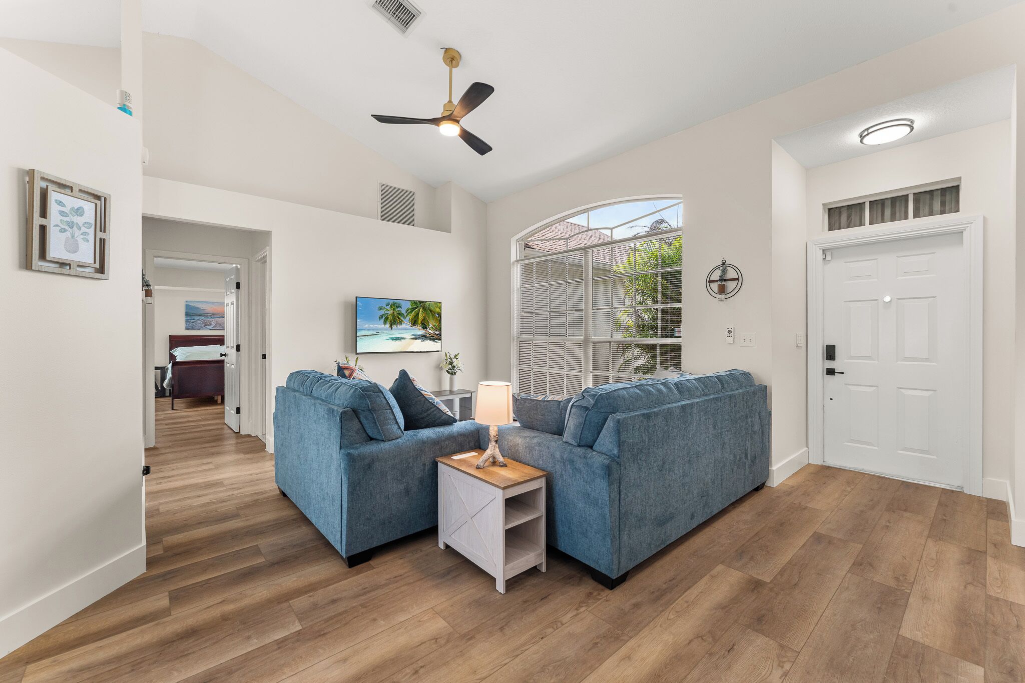 A modern living room with two sofas, a coffee table, and a ceiling fan.