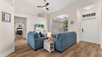 A modern living room with two sofas, a coffee table, and a ceiling fan.