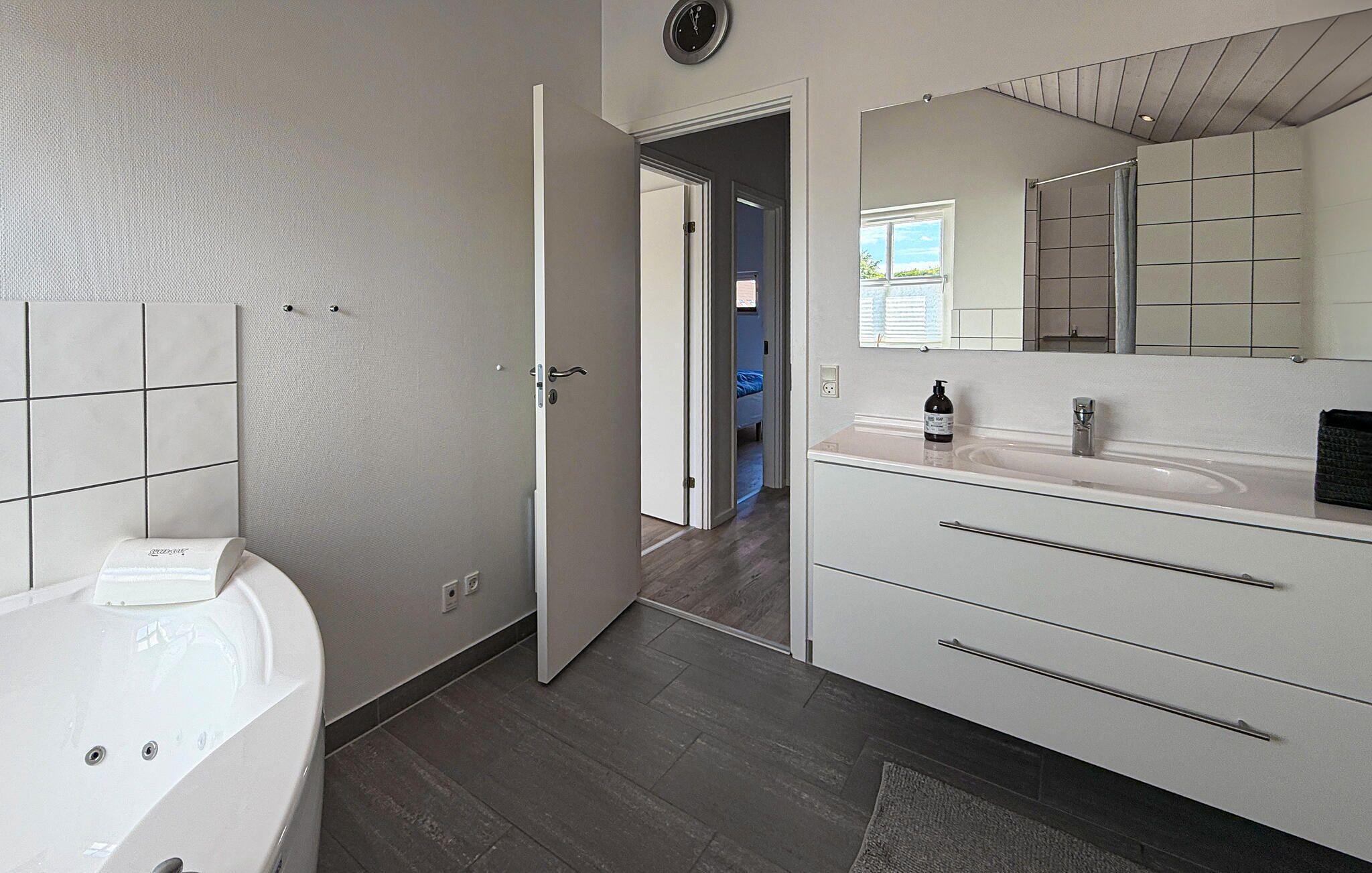 Een moderne badkamer met een badkuip, een grote spiegel en een wastafelmeubel met lades.