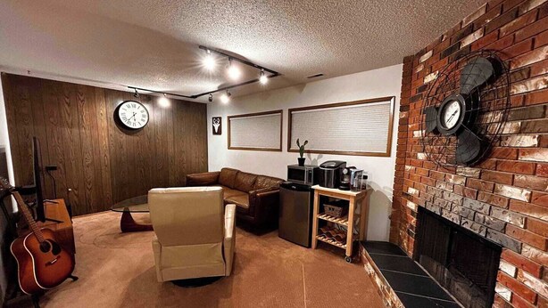 A cozy living room with a fireplace, a sofa, a coffee table, and a guitar. - spacious sunny full house in west hillhurst (Calgary)