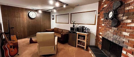 A cozy living room with a fireplace, a sofa, a coffee table, and a guitar.