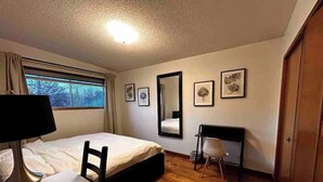 A hotel room with a bed, desk, chair, and a window with curtains. - spacious sunny full house in west hillhurst (Calgary)