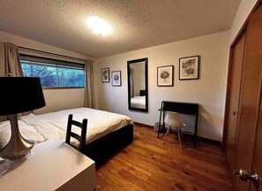 A hotel room with a bed, desk, chair, and a window with curtains. - spacious sunny full house in west hillhurst (Calgary)
