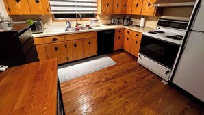 A kitchen with wooden cabinets, a sink, a stove, and a refrigerator. - spacious sunny full house in west hillhurst (Calgary)