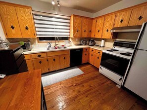 A kitchen with wooden cabinets, a sink, a stove, and a refrigerator. - spacious sunny full house in west hillhurst (Calgary)
