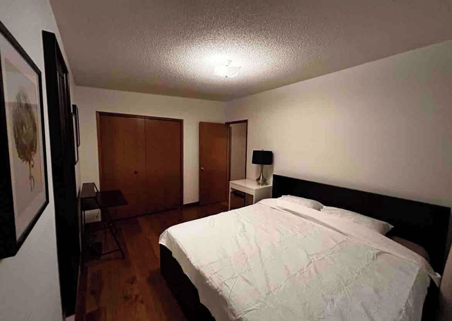 Une chambre à coucher avec un lit, un bureau et deux armoires.