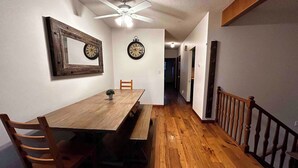 A dining area with a wooden table, chairs, a bench, and two wall clocks. - spacious sunny full house in west hillhurst (Calgary)