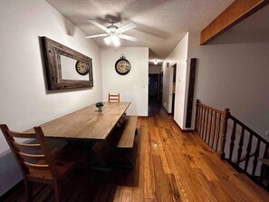 A dining area with a wooden table, chairs, a bench, and two wall clocks. - spacious sunny full house in west hillhurst (Calgary)