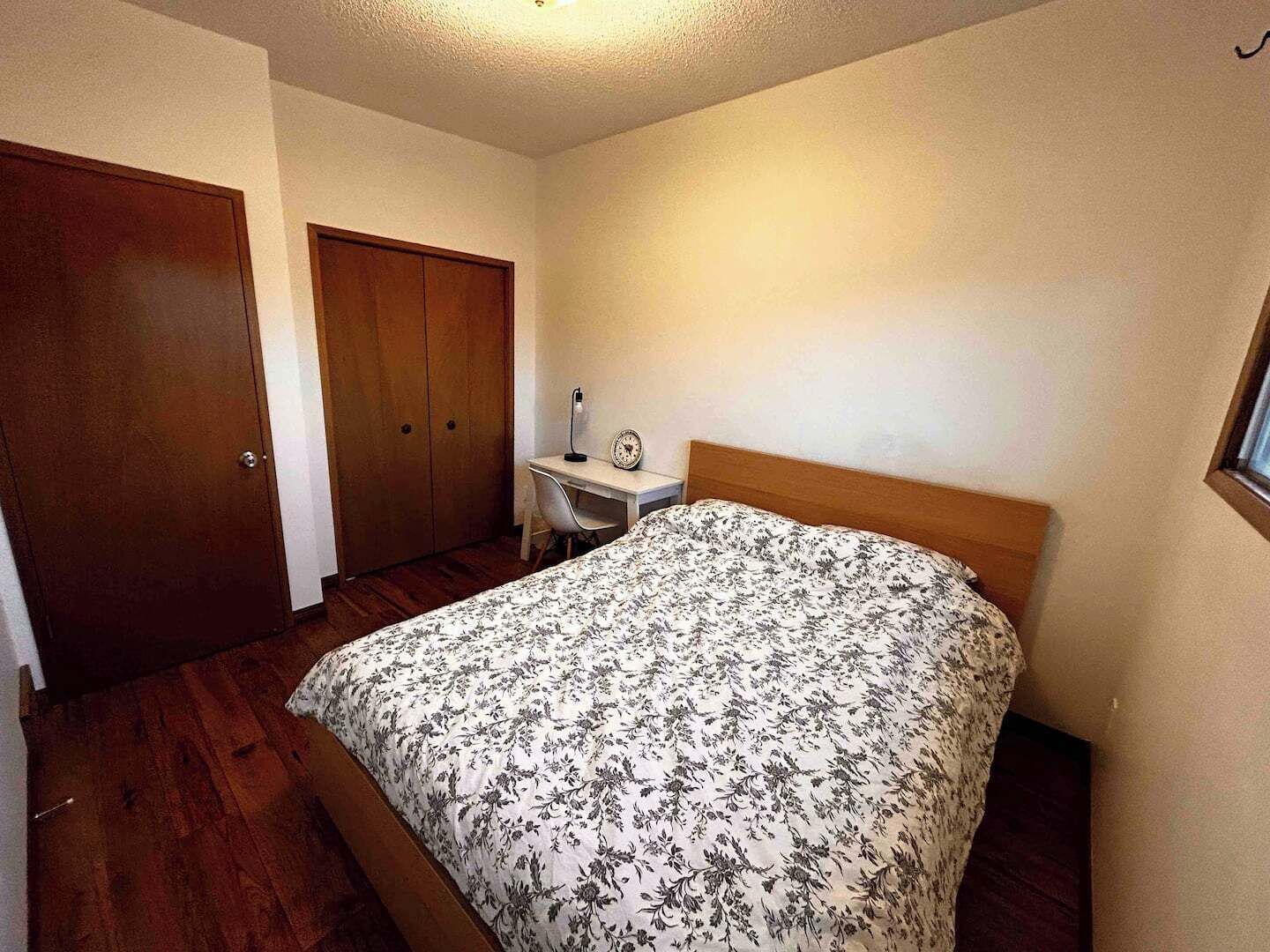 Un dormitorio con cama, escritorio y armario.