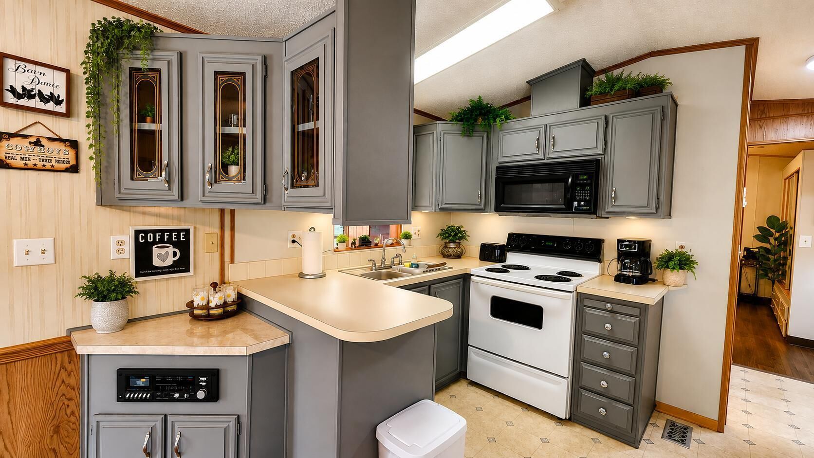 A kitchen with grey cabinets, a microwave, a stove, and a coffee station.