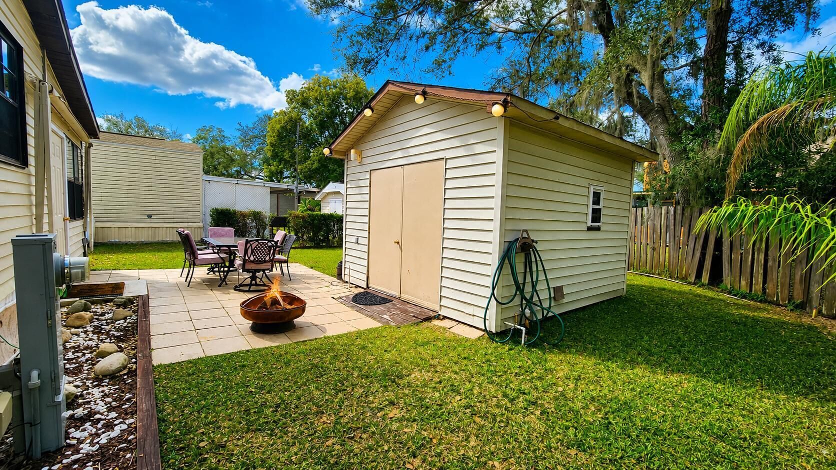 A residential backyard with a fire pit, outdoor seating, and a shed.