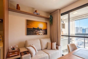 Ein modernes Hotelzimmer mit einer Couch, einem Esstisch und einem großen Fenster mit Blick auf die Stadt.