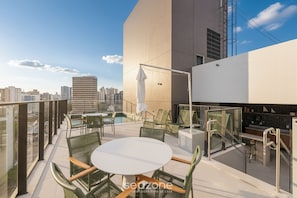 Eine Dachterrasse mit Sitzgelegenheiten im Freien, einem Pool und Blick auf die Stadt.