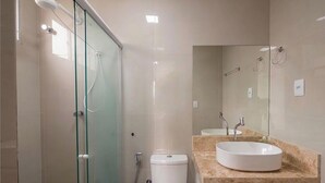 A modern bathroom with a glass shower enclosure, a toilet, a sink with a marble countertop, and a mirror. - Apartment With City Views in Rio Vermelho Jdo0104 (Salvador)