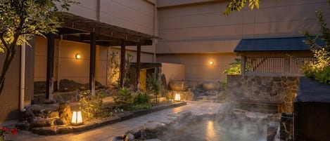 A spa area with a hot spring, stone pathway, and traditional Japanese architecture.