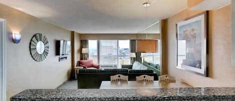 Una habitación de hotel con cocina, una mesa de comedor, un sofá y un ventanal con vistas a la ciudad.