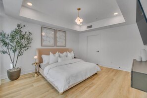 Ein modernes Schlafzimmer mit einem Bett, einer Topfpflanze und einer Deckenleuchte.