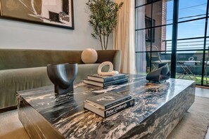 Ein modernes Wohnzimmer mit einem Marmortisch, Büchern und einem grünen Sofa.
