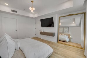 A bedroom with a bed, a TV, a mirror, and a wooden floor. - Modern Loft/Walk To Stadiums/Free Parking! (Atlanta)