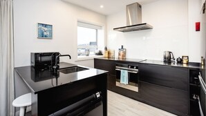 Een moderne keuken met een zwart aanrecht, roestvrijstalen apparatuur en een raam met uitzicht.