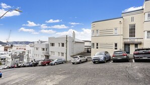 Een parkeerplaats met meerdere auto's, een gebouw met de tekst 'Allen Court' en een hijskraan op de achtergrond.