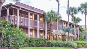 Ein mehrstöckiges Hotel mit Balkonen, Palmen und einem gepflegten Garten.