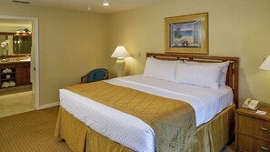 A hotel room with a large bed, a desk with a lamp, a chair, and a bathroom visible through an open door. - Kissimmee | Relaxing Disney Retreat | Pool + Hot Tub (Kissimmee)