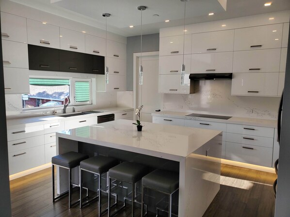 A modern kitchen with a central island, bar stools, and built-in cabinets.