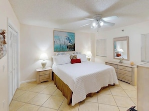A bedroom with a bed, two bedside tables, a ceiling fan, a painting, and a mirror. - Florida Keys Escape Beach, Pool & Marina 2BR (Tavernier)