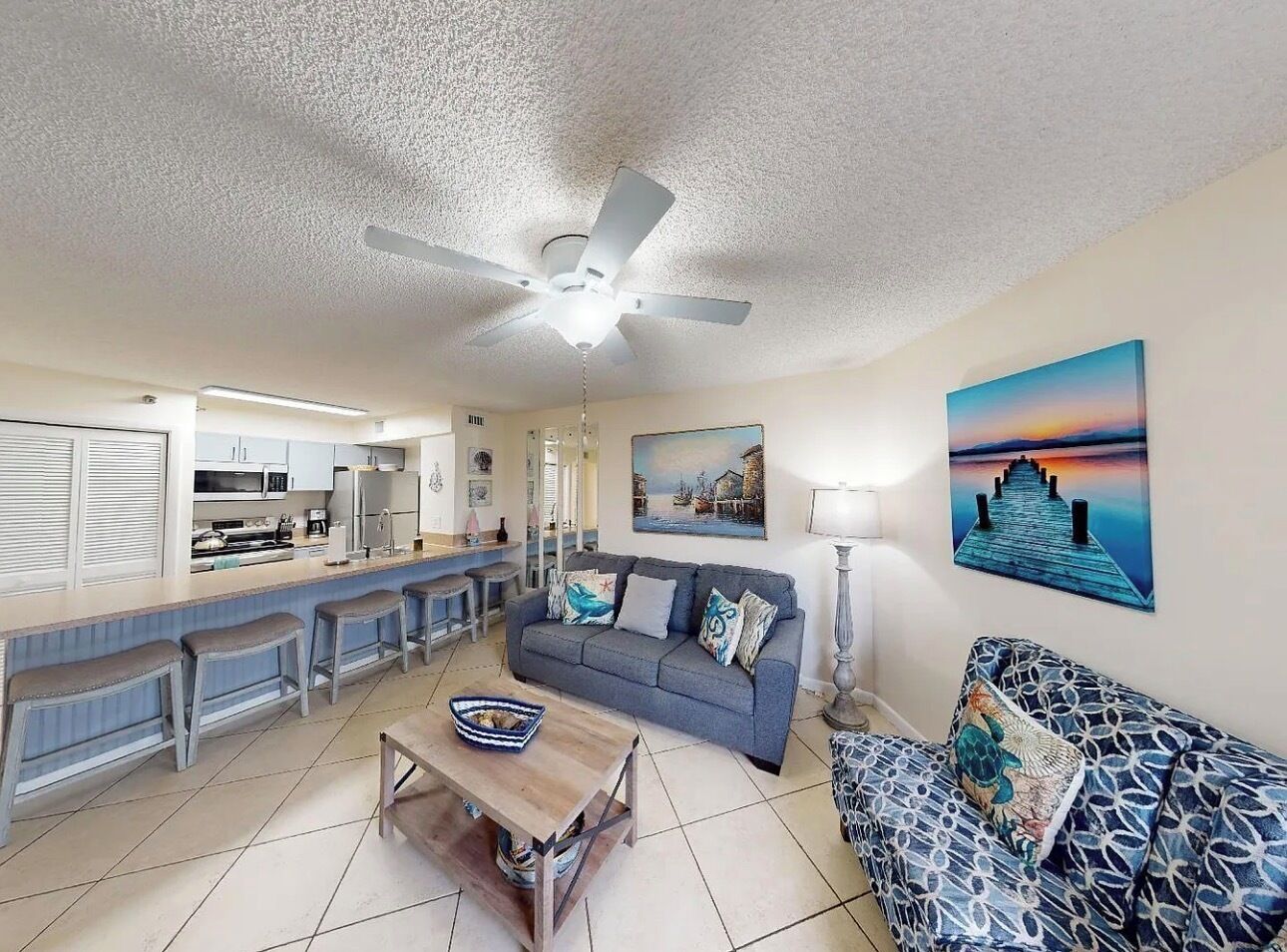 A living room with a sofa, a coffee table, and a dining area with a bar.