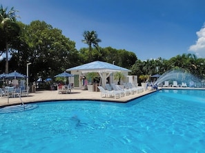A swimming pool with lounge chairs and umbrellas, surrounded by trees. - Florida Keys Escape Beach, Pool & Marina 2BR (Tavernier)