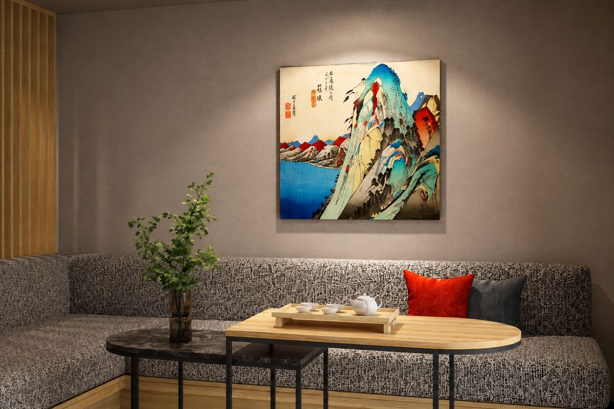 A modern living room with a sofa, a small round table, and a wall-mounted painting.