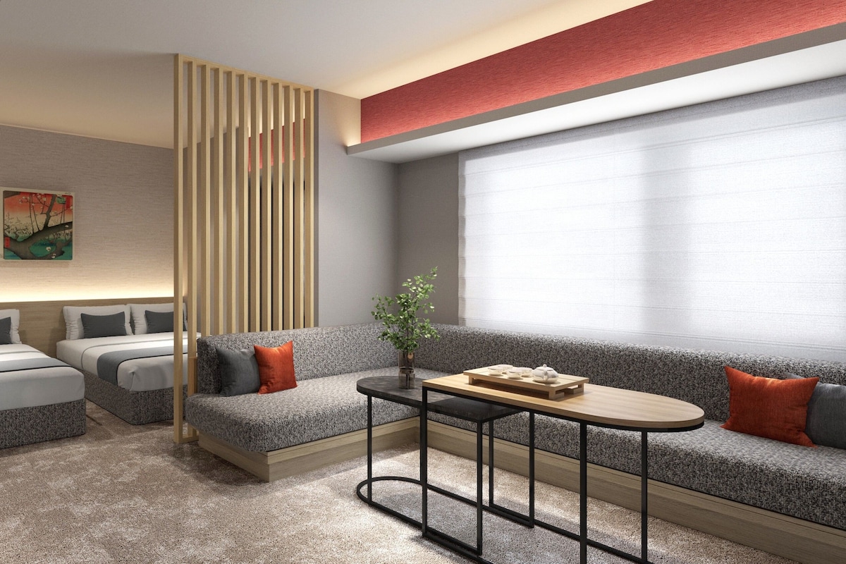 A modern hotel room with a sofa set, a small table, a decorative plant, and a painting on the wall.