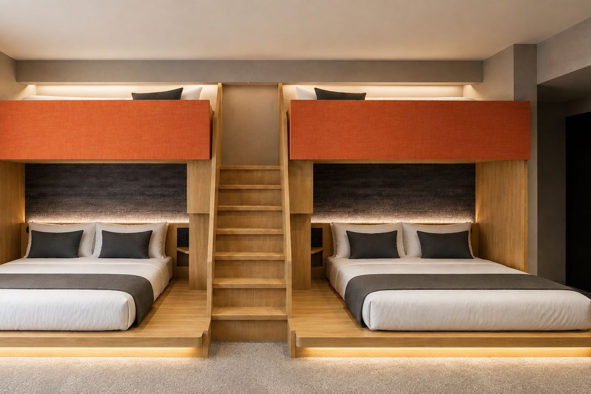 A room with two bunk beds, each with a headboard and a mattress, and a central staircase.