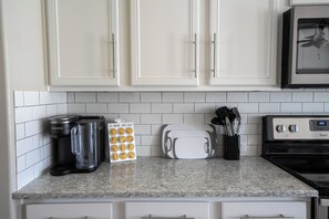 A kitchen with white cabinets, a coffee maker, a toaster, and a microwave.