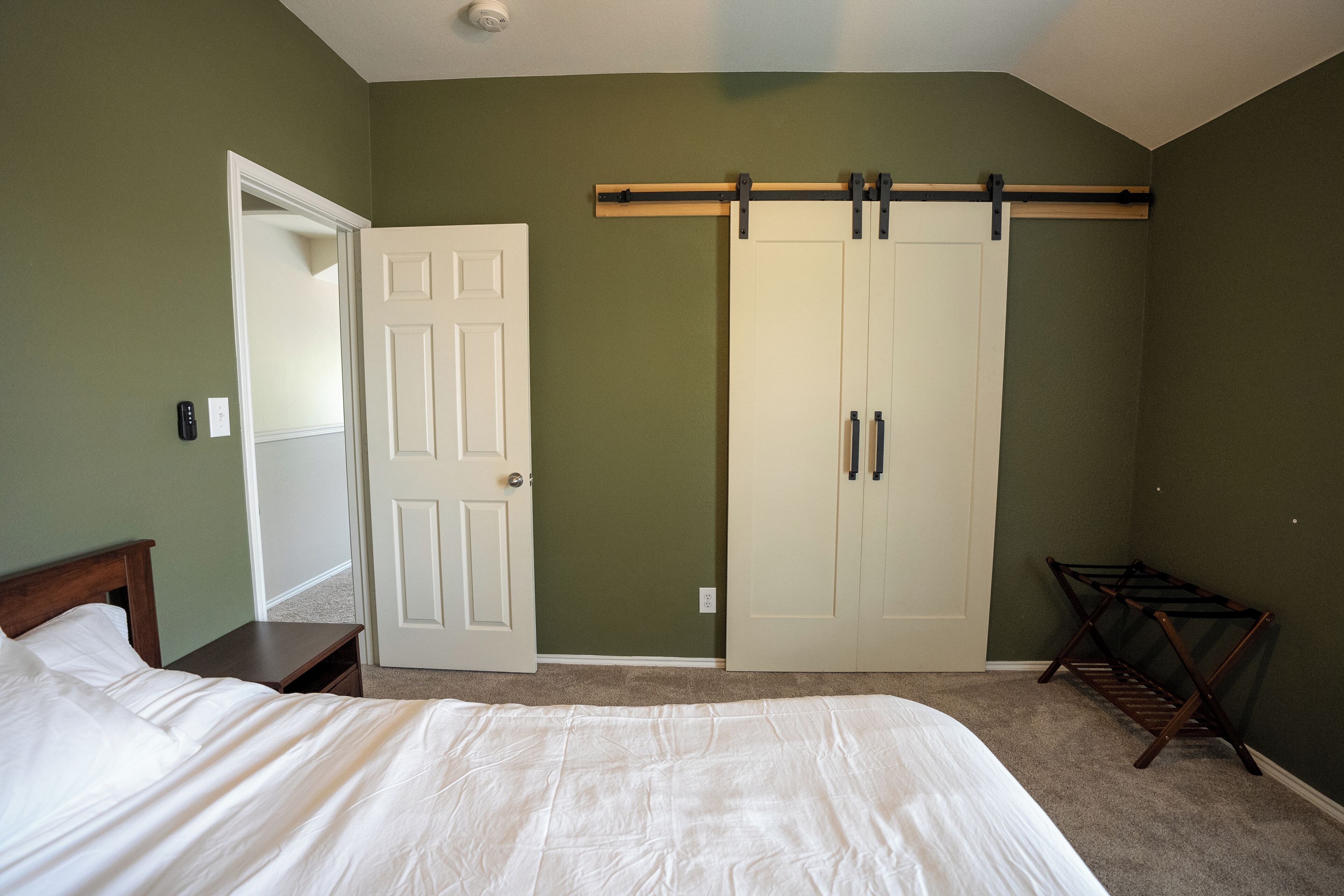 Une chambre à coucher avec un lit, une armoire, un miroir et une chaise.