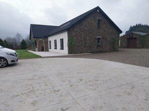 A two-story stone building with a sloped roof, a driveway, and a parked car. - House Sleeps 11 with Parking (Tralee)